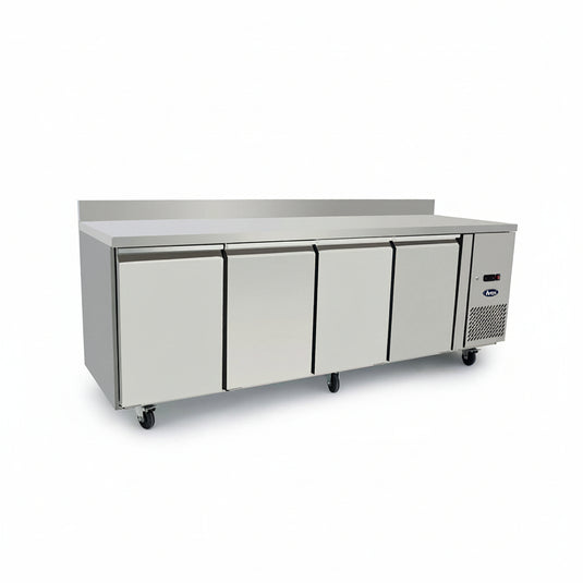 A commercial undercounter refrigerator with four front doors, a stainless steel work surface, and a side-mounted cooling unit, shown on a plain white background.